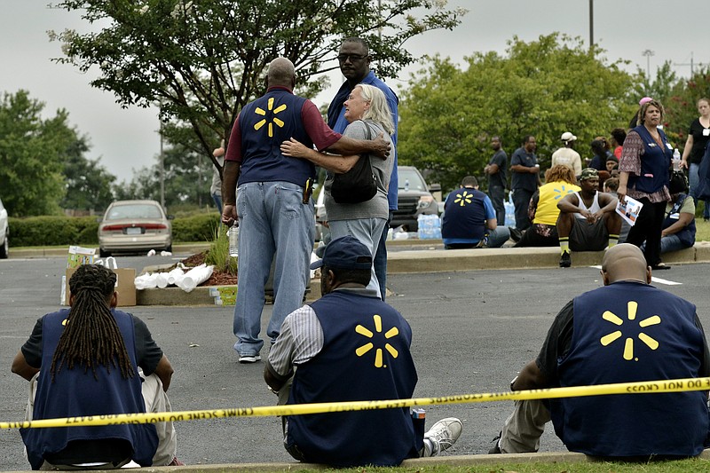 FILE - In this July 30, 2019, file photo Walmart employees gather in a nearby parking lot after a shooting at the store in Southaven, Miss. The discounter has dealt with thousands of violent crimes at its stores across the country, including one that took place less than a week ago at a store in Mississippi where a disgruntled worker killed two co -workers and wounded a police officer. (AP Photo/Brandon Dill, File)