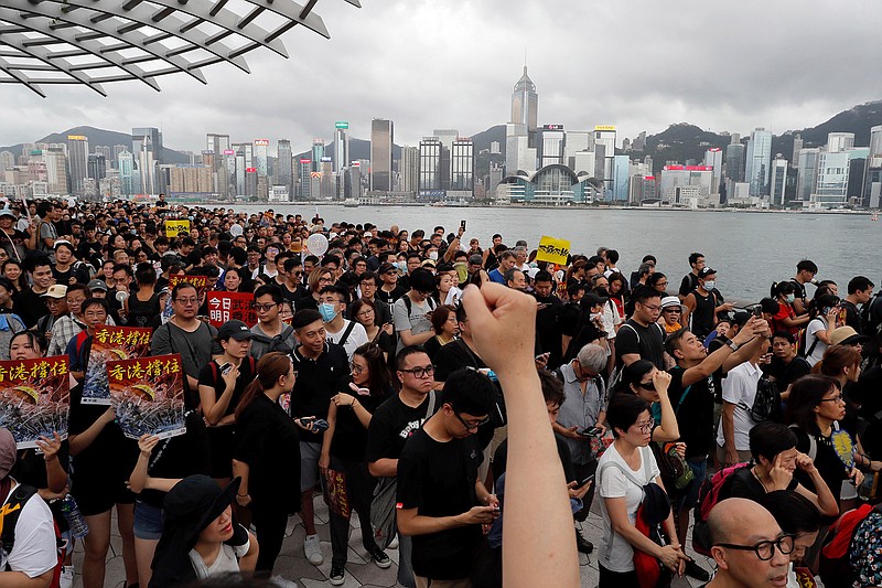 In this July 7, 2019, file photo, protesters march near the skyline of Hong Kong. China's central government has dismissed Hong Kong pro-democracy protesters as clowns and criminals while bemoaning growing violence surrounding the monthslong demonstrations.(AP Photo/Kin Cheung, File)