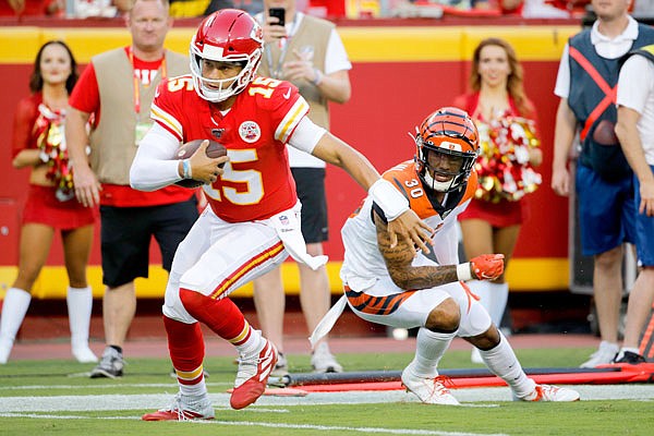 Chiefs quarterback Patrick Mahomes runs away from Bengals safety Jessie Bates III (30) during the first half of Saturday night's preseason game at Arrowhead Stadium.