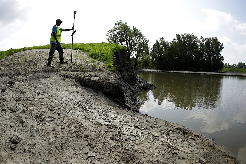 In this Tuesday, Aug. 6, 2019 photo, U.S. Army Corps of Engineers worker Ron Allen uses a GPS tool to survey the extent of damage where a levee failed along the Missouri River near Saline City, Mo. (AP Photo/Charlie Riedel)