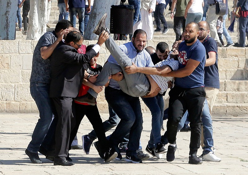 Palestinians carry injured person during clashes with Israeli police at al-Aqsa mosque compound in Jerusalem, Sunday, Aug 11, 2019. Clashes have erupted between Muslim worshippers and Israeli police at a major Jerusalem holy site during prayers marking the Islamic holiday of Eid al-Adha. (AP Photo/Mahmoud Illean)