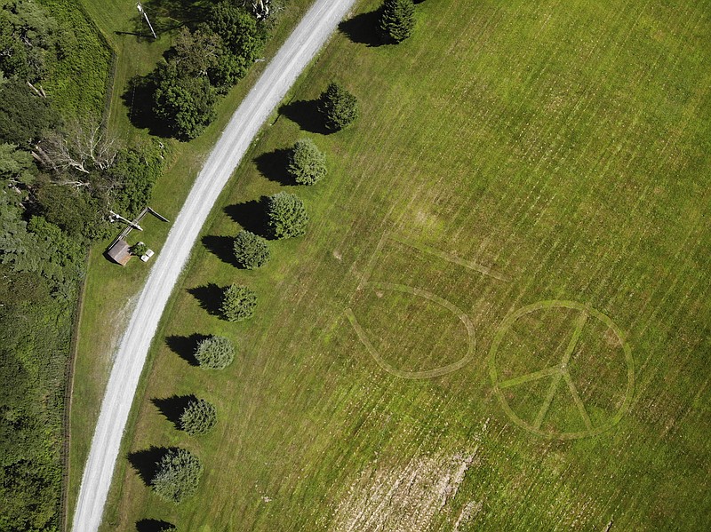 This Wednesday, July 24, 2019, photo shows the number 50 and a peace sign mowed into the grass at the site of the 1969 Woodstock Music and Arts Fair in Bethel, N.Y. Fifty years later, memories of the rainy weekend Aug. 15-18, 1969, remain sharp among people who were in the crowd and on the stage. (AP Photo/Seth Wenig)