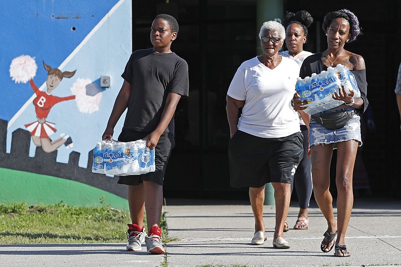 Rahjiah McBride, of Chester, Pa., right, helps her relatives, Newark residents Elnora and Bowdell Goodwin, center and second right, as Goodwin's son pitches in carrying bottled water from the Boylan Street Recreation Center, Monday, Aug. 12, 2019, in Newark, N.J. New Jersey's governor and Newark's mayor vowed to provide bottled water to city residents with lead service lines after Environmental Protection Agency tests indicated that filters distributed earlier might not be protecting residents of some areas against elevated lead levels. (AP Photo/Kathy Willens)