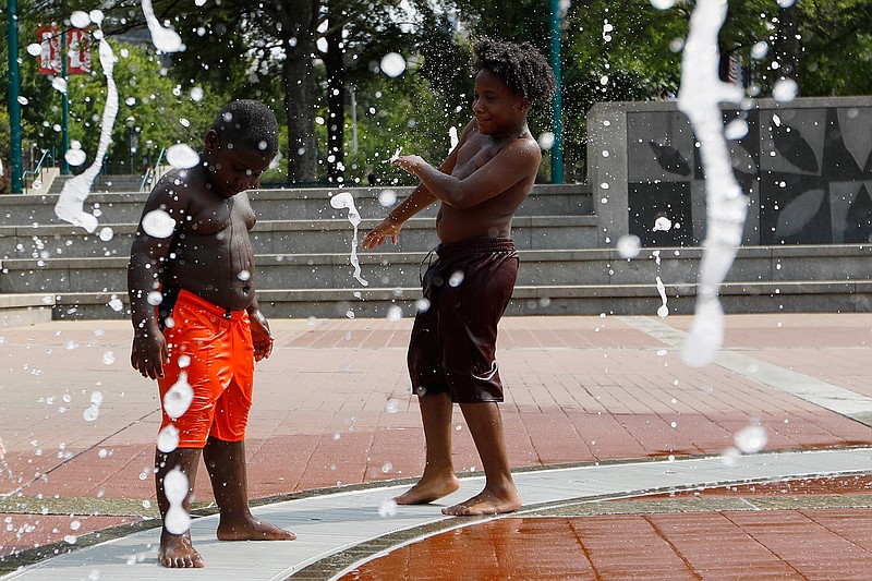  Kai Frazier and Chance Seawright, brothers visiting from Aiken, South Carolina, cool off while playing in the Fountain of Rings in Centennial Olympic Park on Monday in Atlanta, Georgia.