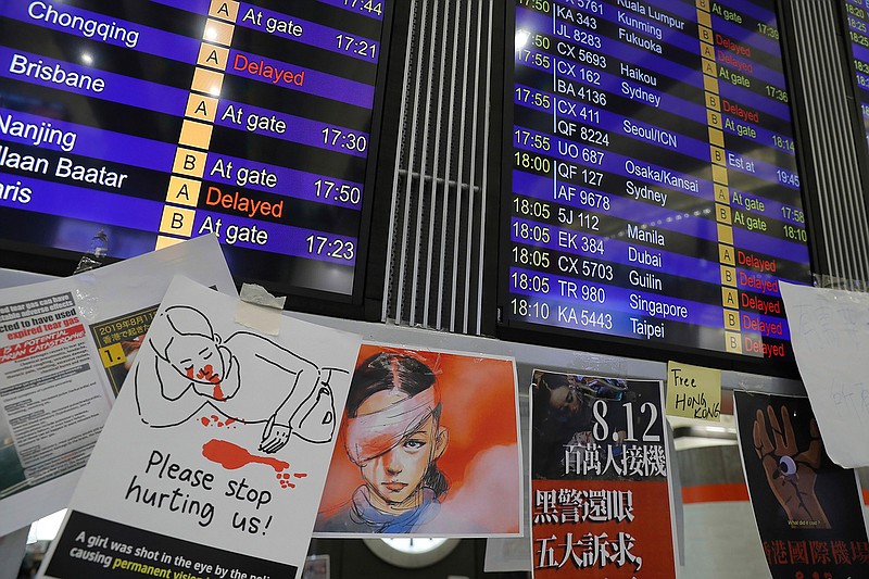 Protest placards are placed around the flight information board Monday, Aug. 12, 2019, as thousands of pro-democracy protesters stage a sit-in at Hong Kong International Airport. One of the world's busiest airports canceled all flights after the protesters crowded into the main terminal on Monday afternoon.