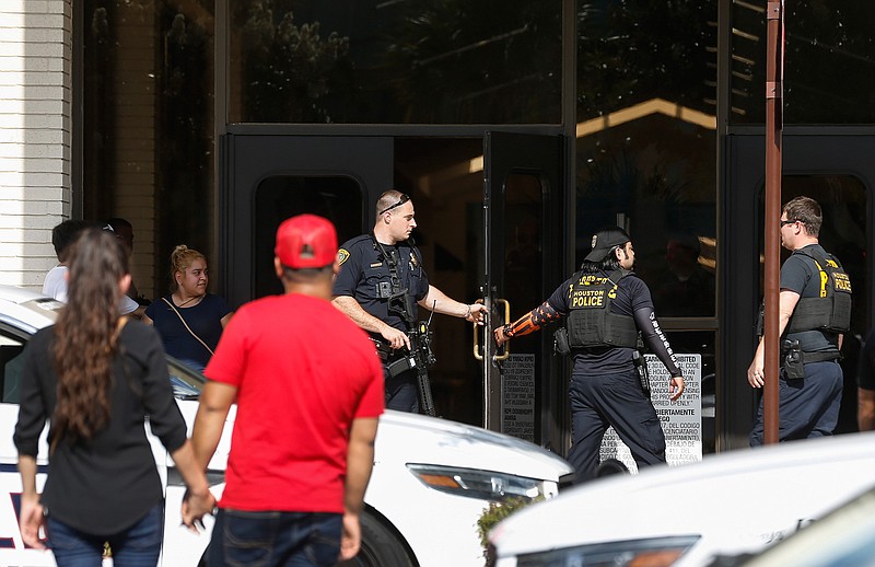 People stand outside Memorial City Mall on Sunday in Houston as police investigate a disturbance causing an evacuation of the shopping center. Hundreds of panicked people rushed out of the Texas mall after a masked man jumped on a food court table and said he would kill himself before throwing down an unknown object covered in toilet paper. 