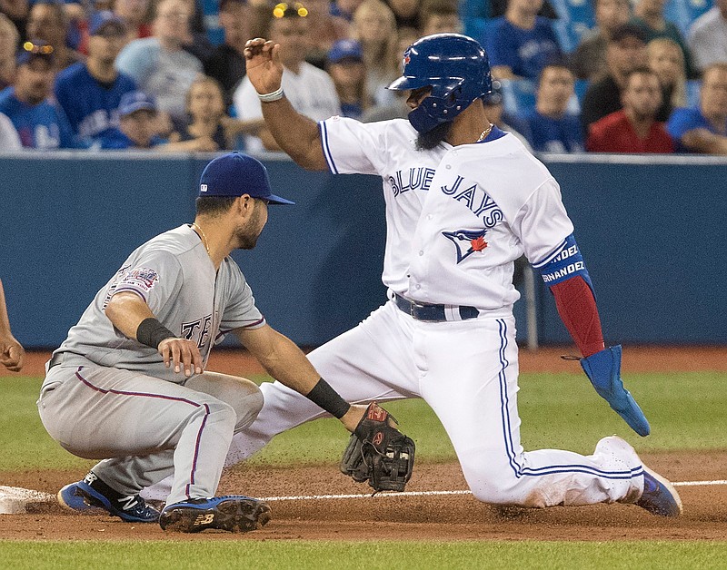 Toronto Blue Jays' Teoscar Hernandez, right, is tagged out by Texas Rangers' Isiah Kiner-Falefa while trying to steal third during third-inning baseball game action in Toronto, Monday, Aug. 12, 2019. (Fred Thornhill/The Canadian Press via AP)