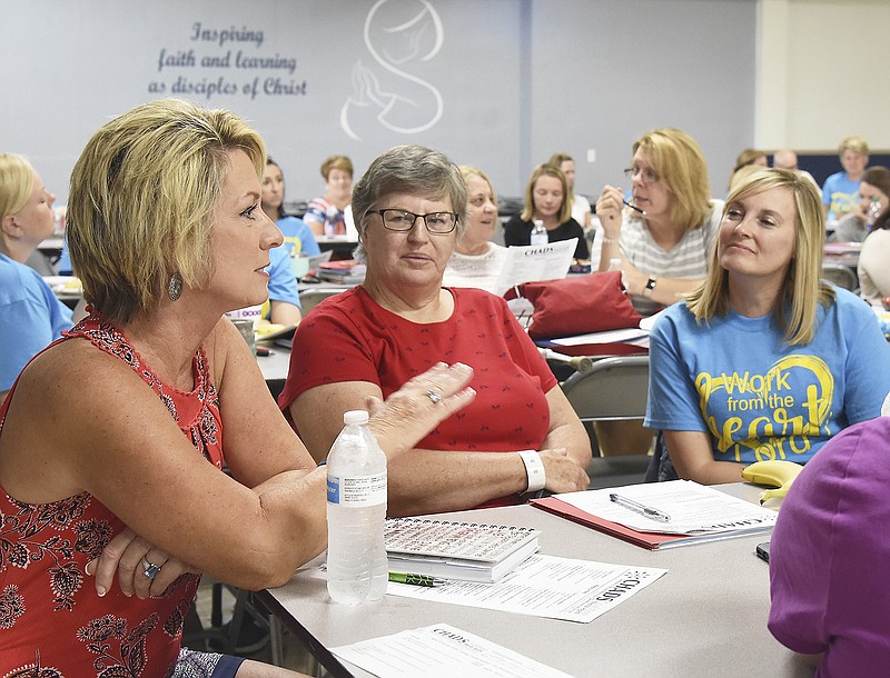 Kay Scott, left, talks during a breakout session Monday as Colleen Pace delivers a presentation to teachers to learn the signs of suicide in youth. Seated with Scott are Phyllis Emmel, second from left, with Helias High School, and Beth Atkison, with Immaculate Conception School.