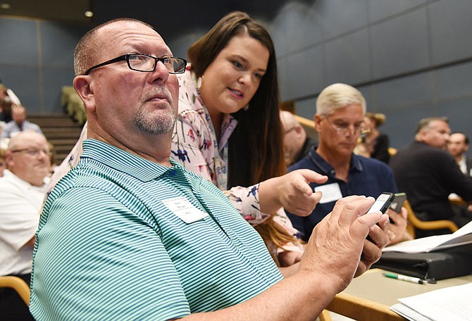 Steve Bryant looks to the screen as Brittany Ruess assists him with the smartphone app that creates an instant result on the screen. Bryant works for the Department of Elementary and Secondary Education, and Ruess works for the Office of Administration, assisting participants with technical issues if needed.