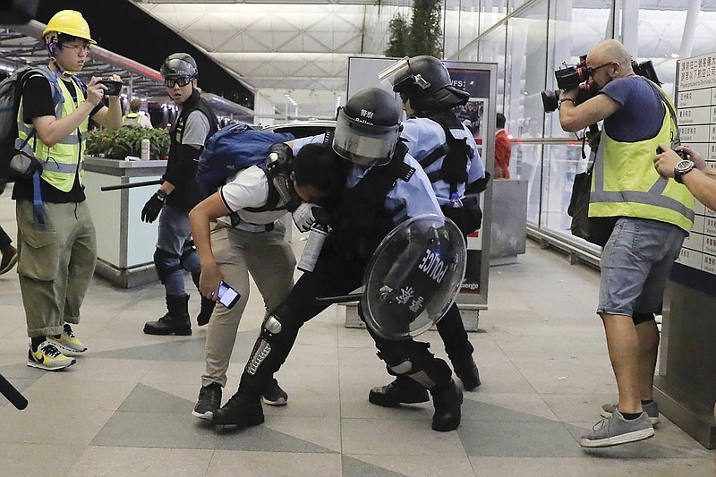 Policemen in riot gears arrest a protester during a demonstration at the Airport in Hong Kong, Tuesday, Aug. 13, 2019. Chaos has broken out at Hong Kong's airport as riot police moved into the terminal to confront protesters who shut down operations at the busy transport hub for two straight days. (AP Photo/Kin Cheung)