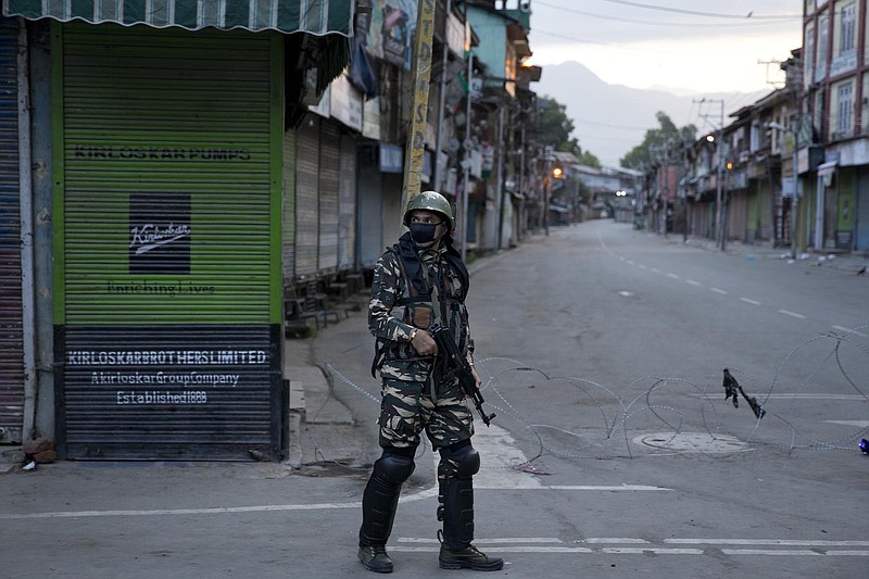 FILE- In this Friday, Aug. 9, 2019 file photo, an Indian Paramilitary soldier patrols during curfew in Srinagar, Indian controlled Kashmir. The main city in the India-administered part of the disputed Himalayan region of Kashmir has turned into a vast maze of razor wire coils and steel barricades as drones and helicopters hover overhead. Wearing flak jackets and riot gear, paramilitary soldiers carry automatic rifles and shotguns to control the network of checkpoints and barricades across roads, lanes and intersections in Srinagar. (AP Photo/ Dar Yasin, File)