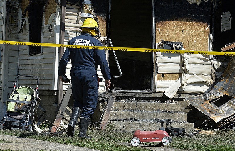 Erie Bureau of Fire Inspector Mark Polanski helps investigate a fatal fire at 1248 West 11th St. in Erie, Pa, on Sunday, Aug. 11, 2019. Authorities say an early morning fire in northwestern Pennsylvania claimed the lives of multiple children and sent another person to the hospital. (Greg Wohlford/Erie Times-News via AP)