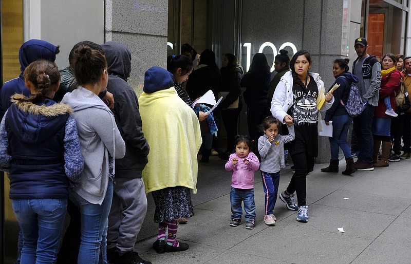 File - In this Jan. 31, 2019, file photo, hundreds of people overflow onto the sidewalk in a line snaking around the block outside a U.S. immigration office with numerous courtrooms in San Francisco. Santa Clara and San Francisco have filed suit against the Trump administration over its new controversial "public charge" rule that restricts legal immigration. This lawsuit is the first after the Department of Homeland Security's announcement Monday, Aug. 12, 2019, that it would deny green cards to migrants who use Medicaid, food stamps, housing vouchers or other forms of public assistance. (AP Photo/Eric Risberg, File)