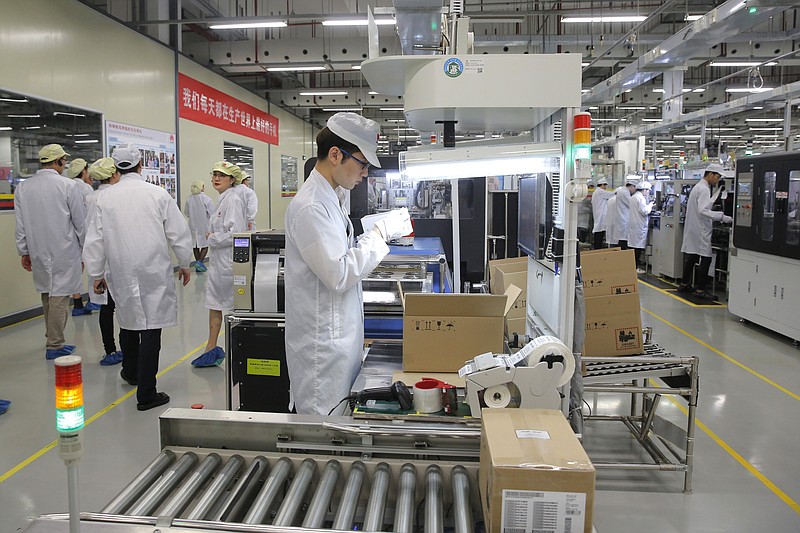 FILE - In this March 6, 2019, file photo a staff member works on a mobile phone production line during a media tour in Huawei factory in Dongguan, China's Guangdong province. Huawei Technologies Co. is one of the world's biggest supplier of telecommunications equipment. The United States is delaying tariffs on Chinese-made cellphones, laptop computers and other items and removing other Chinese imports from its target list altogether in a move that triggered a rally on Wall Street. (AP Photo/Kin Cheung, File)