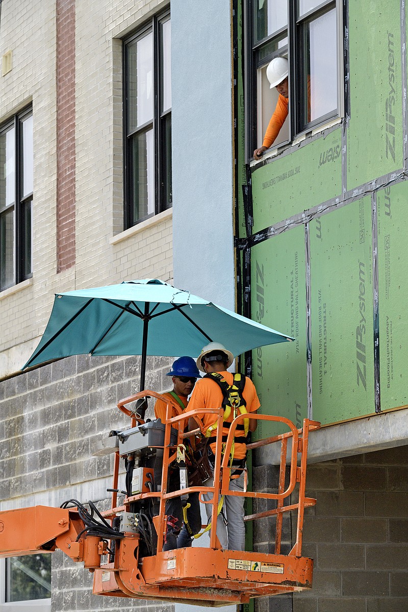 A construction crew keeps out of the sun with a sun umbrella on their boom lift as they work on an apartment building along S. Jefferson Davis Parkway in New Orleans, La. Tuesday, Aug. 13, 2019. National Weather Service issued a heat advisory for the New Orleans area Tuesday. 
  (Max Becherer/The Advocate via AP)