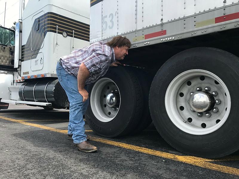 In this June 13, 2019 photo, truck driver Terry Button looks over his trailer during at stop in Opal, Va. The Trump administration has moved a step closer to relaxing federal regulations governing the amount of time truck drivers can spend behind the wheel.  (AP Photo/Tom Sampson)