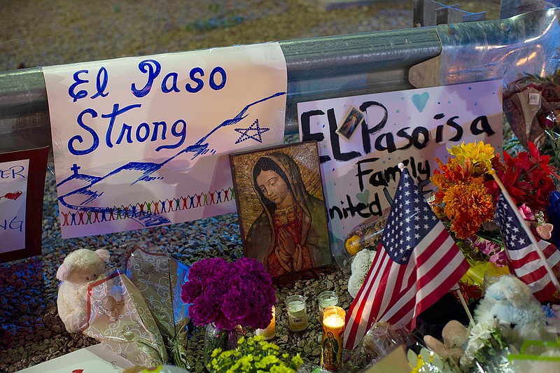 In this Aug. 4, 2019 file photo, a Virgin Mary painting, flags and flowers adorn a makeshift memorial for the victims of the mass shooting at a Walmart in El Paso, Texas. A man whose 63-year-old wife was among the Texas mass shooting victims says he has no other family and welcomes anyone wanting to attend her services in El Paso. Margie Reckard was among 22 people fatally shot on Aug. 3 at a the Walmart. Reckard and Antonio Basco were married 22 years. (AP Photo/Andres Leighton, File)