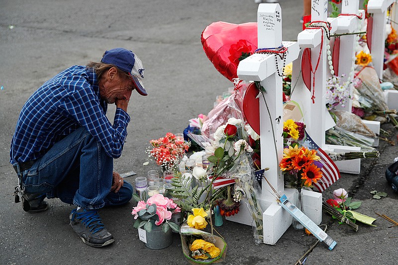 In this Aug. 6, 2019 file photo, Antonio Basco cries beside a cross at a makeshift memorial near the scene of a mass shooting at a shopping complex, in El Paso, Texas. Basco, whose 63-year-old wife was among the Texas mass shooting victims says he has no other family and welcomes anyone wanting to attend her services in El Paso. Margie Reckard was among 22 people fatally shot on Aug. 3 at a the Walmart. Reckard and Basco were married 22 years. (AP Photo/John Locher, File)