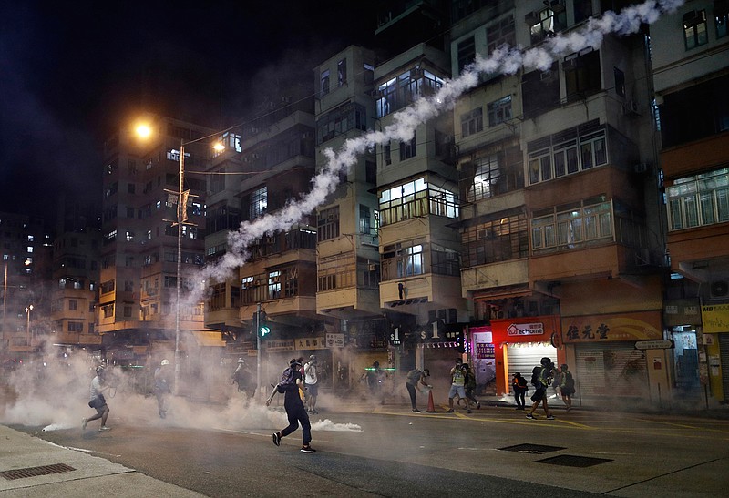 Protesters react to tear gas from Shum Shui Po police station in Hong Kong on Wednesday, Aug. 14, 2019. German Chancellor Angela Merkel is calling for a peaceful solution to the unrest in Hong Kong amid fears China could use force to quell pro-democracy protests.(AP Photo/Vincent Yu)