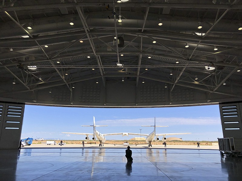 Virgin Galactic ground crew guide the company's carrier plane into the hangar at Spaceport America following a test flight over the desert near Upham, New Mexico, on Thursday, Aug. 15, 2019. The carrier plane is now permanently based at the spaceport after arriving earlier this week. (AP Photo/Susan Montoya Bryan)