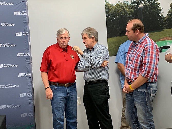 Missouri Gov. Mike Parson, U.S. Sen. Roy Blunt and U.S. Rep. Jason Smith confer before a press conference Thursday, Aug. 15, 2019, at the Missouri State Fair.