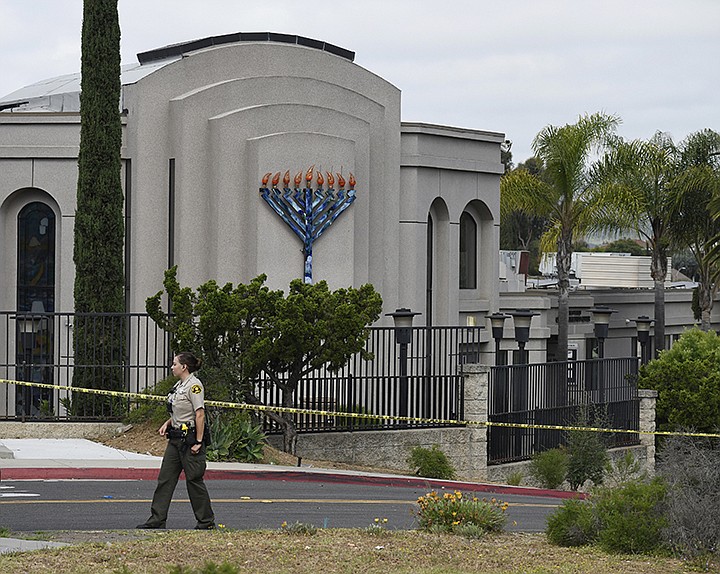 In this Sunday, April 28, 2019 file photo, a San Diego county sheriff's deputy stands in front of the Chabad of Poway synagogue, in Poway, Calif. A 19-year-old nursing student who opened fire at the California synagogue in April didn't have a valid hunting license, which is the only way someone under 21 who isn't in the military or law enforcement can legally buy a weapon under state law. The California Fish and Wildlife Department said Wednesday, Aug. 14, 2019, that John T. Earnest was issued a hunting license, but it had not gone into effect yet. It's unclear how Earnest bought the gun. (AP Photo/Denis Poroy, File)