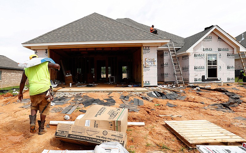 In this June 19, 2019, file photo a worker carries shingles for a roof of a house under construction in a Brandon, Miss., neighborhood. On Friday, Aug. 16, the Commerce Department reports on U.S. home construction in July. (AP Photo/Rogelio V. Solis, File)