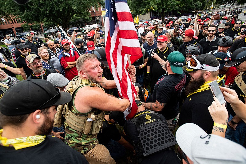 Joseph Oakman and fellow Proud Boys plant a flag in Tom McCall Waterfront Park during an "End Domestic Terrorism" rally in Portland, Ore., on Saturday, Aug. 17, 2019.  Portland Mayor Ted Wheeler said the situation was "potentially dangerous and volatile" but as of early afternoon most of the right-wing groups had left the area via a downtown bridge and police used officers on bikes and in riot gear to keep black clad, helmet and mask-wearing anti-fascist protesters — known as antifa — from following them.  (AP Photo/Noah Berger)
