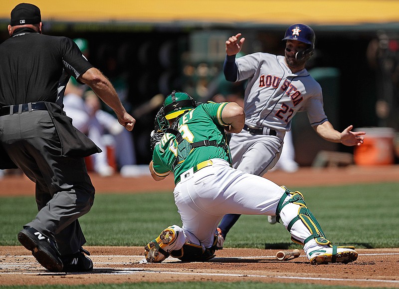 Houston Astros' Jose Altuve, right, is tagged out by Oakland Athletics catcher Josh Phegley on Sunday, Aug. 18, 2019, in the first inning in Oakland, Calif. 