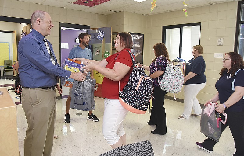 Todd Shalz, at left, accepts school supplies from Eileen Pierson and her co-workers as they deliver the items to Callaway Hills Elementary School where Shalz is principal. Pierson is president of DOC's Personnel Club and organized the opportunity for her and fellow staffers to help others. She and other staffers from the club at Department of Corrections, which also includes staff of Probation and Parole, collected funds dedicated to purchasing school supplies for elementary school students. Along with the supplies purchased with the monetary donations, employees brought items individually to add to the stack to take to the Jefferson City Public Schools elementary school. 