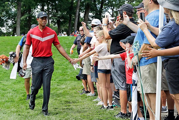Tiger Woods greets fans as he walks to the 14th fairway after hitting his tee shot during Sunday's final round of the BMW Championship at Medinah Country Club in Medinah, Ill.
