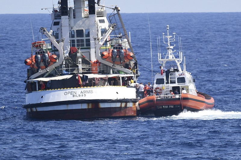 An Italian Coast Guard boat, right, approaches the Spanish humanitarian rescue ship Open Arms, off the Sicilian island of Lampedusa, southern Italy, Tuesday, Aug. 20, 2019. At least 15 more migrants jumped into the sea Tuesday from the Open Arms rescue ship in desperate bids to reach the shores of Italy after 19 days on the boat in deteriorating conditions as Italy refuses to open its ports. With the situation on board described by Open Arms as "out of control" and "desperate" over Italy's repeated refusal to allow the migrants into the southern island of Lampedusa, Spain said it was dispatching a naval ship to escort the aid group's boat and its passengers to a port in the Spanish island of Mallorca. (AP Photo/Salvatore Cavalli)
