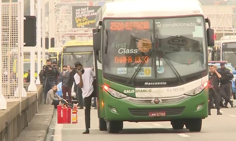 In this frame grab from video provided by TV Globo, an armed man who took dozens of hostages on a bus, steps outside of the bus momentarily on the bridge connecting the city of Niteroi to Rio de Janeiro, Brazil, Tuesday, Aug. 20, 2019. The man threatened to set the vehicle on fire with gasoline before police shot him dead in a four-hour standoff broadcast live on television. (TV Globo via AP)