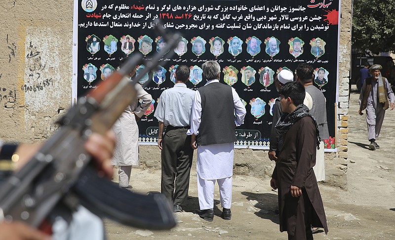 Afghans look at a banner displaying photographs of victims of the Dubai City wedding hall bombing during a memorial service, in Kabul, Afghanistan, Tuesday, Aug. 20, 2019. Hundreds of people have gathered in mosques in Afghanistan's capital for memorials for scores of people killed in a horrific suicide bombing at a Kabul wedding over the weekend.(AP Photo/Rafiq Maqbool)
