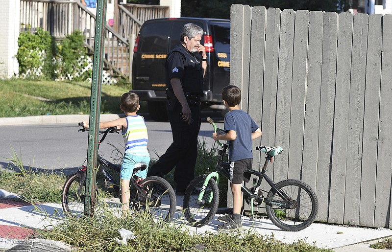 Two boys watch as a Detroit police officer investigates a fatal dog attack on a young girl who later died of her injuries in Detroit on Monday, Aug. 19, 2019. Police say the owner of three dogs is in custody after the animals killed Emma Hernandez, 9, as she rode a bike. The girl's father, Armando Hernandez, says the man was warned that a fence was too flimsy to hold the dogs.  (Max Ortiz/Detroit News via AP)