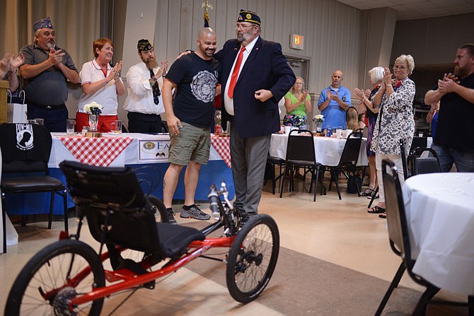 Marine Corps and Army veteran Scott Sanning is hugged by American Legion Post 5 Commander Jim Rosenberg on Tuesday, Aug. 20, 2019, as he is presented with his new tricycle during the American Legion Installation of Officers Ceremony.