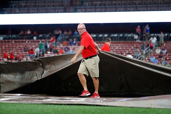 A member of the Busch Stadium grounds crew covers the field at the start of a rain delay during the eighth inning of Wednesday night's game between the Cardinals and the Brewers in St. Louis.