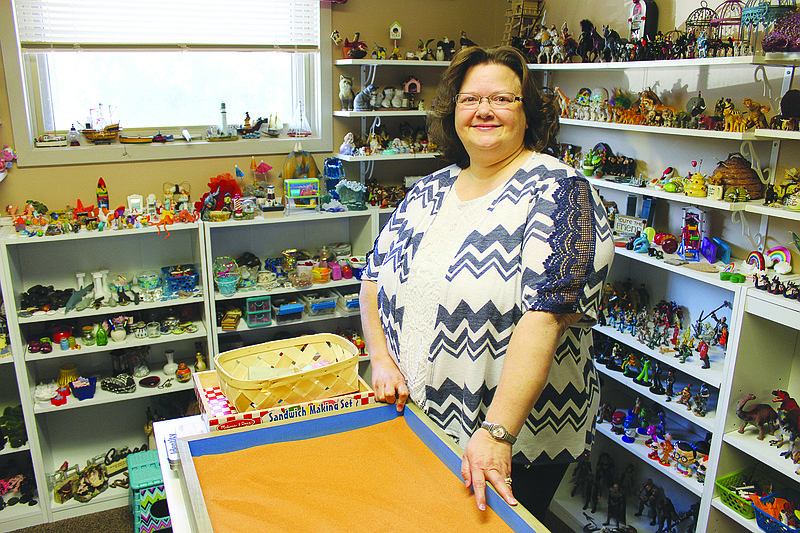 Registered Play Therapist-Supervisor Cathy Figgins stands next to her office's sandtray, figures and statuettes filling the background. Figgins was awarded the Kathryn Boone Outstanding Play Therapist Award by the Missouri Association for Play Therapy last June.