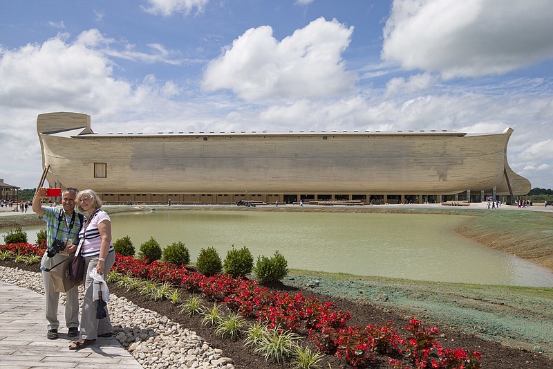 FILE - In a July 5, 2016 file photo, visitors take a selfie as a replica Noah's Ark stands in the distance at the Ark Encounter theme park during a media preview day, in Williamstown, Ky.  Grant County’s school board in Kentucky says the Ark Encounter theme park with a 500-foot long Noah’s Ark is not paying enough in property taxes. (AP Photo/John Minchillo, File)