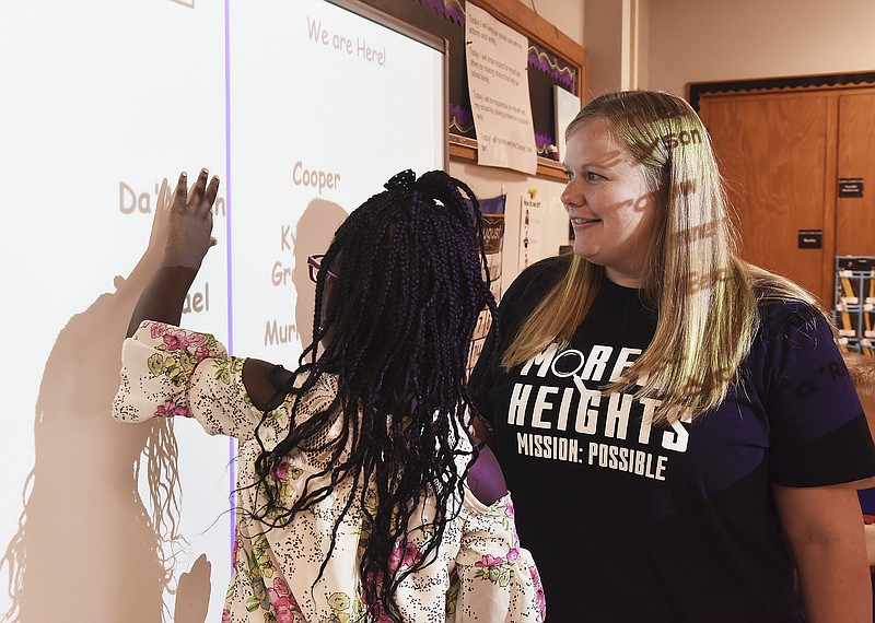 FILE: Lindsey Hammann helps her young student, DaMiyah Prince, find her name on the white board to drag it to the other side to indicate that she is in the classroom on the first day of this new school year. Hammann is a kindergarten teacher at Moreau Heights Elementary School and helped the students locate their name so they could learn it by seeing it and let the rest of the class know they were in attendance. 