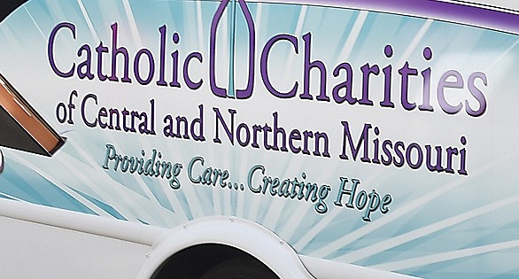 The Catholic Charities for Central and Northeast Missouri logo is displayed on a bus used by the organization.