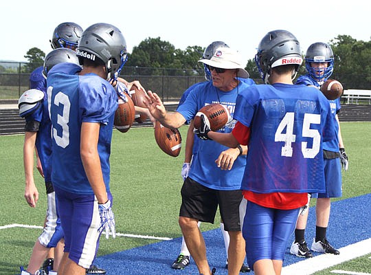 South Callaway assistant coach Bill Frazee (center) works on a ball-gripping drill with the wide receivers during practice earlier this month at the high school in Mokane.