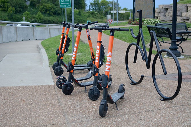 A group of SPIN scooters are parked in a line Thursday along the Pat Jones Pedestrian Bicycle Lane. The Jefferson City Public Safety Committee has proposed an amendment to group "motorized bicycles," like Segways, in the same category as the SPIN electric scooters, which would allow their use within city limits.