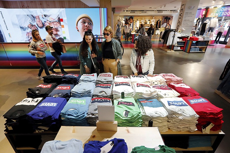 In this June 14, 2019, photo a pair of shoppers, center, in the Levi's store in New York's Times Square, survey a T-shirt display. On Friday, Aug. 30, the Commerce Department issues its July report on consumer spending, which accounts for roughly 70 percent of U.S. economic activity. (AP Photo/Richard Drew)