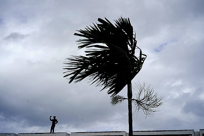 A man stands on a store's roof Sunday as he prepares it for the arrival of Hurricane Dorian in Freeport on Grand Bahama, Bahamas.