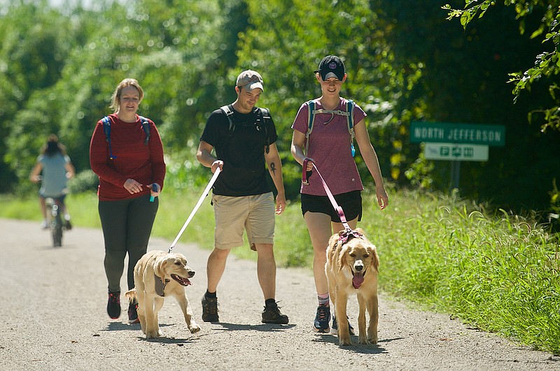 From left, Morgan Weaver, brother Will Weaver and Megan West walk two golden retrievers along the Katy Trail late Monday morning. Ellie (left) and Atti seemed to enjoy the sunny weather.