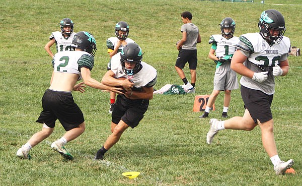North Callaway senior quarterback Jadon Henry hands the ball off to junior halfback Cody Cash during practice last month at the high school in Kingdom City.