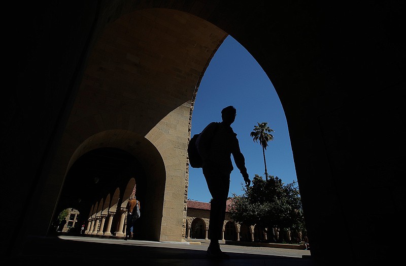 Pedestrians move through a colonnade April 9 on the campus of Stanford University in Stanford, Calif. College students who earned money this summer can make the most of it by including longer-term goals in their financial plan.