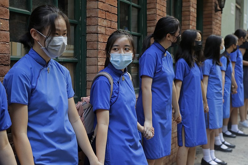 Students wearing mask hold hands to surround St. Stephen's Girls' College in Hong Kong, Monday, Sept. 9, 2019. Thousands of demonstrators in Hong Kong urged President Donald Trump to "liberate" the semiautonomous Chinese territory during a peaceful march to the U.S. Consulate on Sunday, but violence broke out later in the business and retail district as police fired tear gas after protesters vandalized subway stations, set fires and blocked traffic. (AP Photo/Kin Cheung)