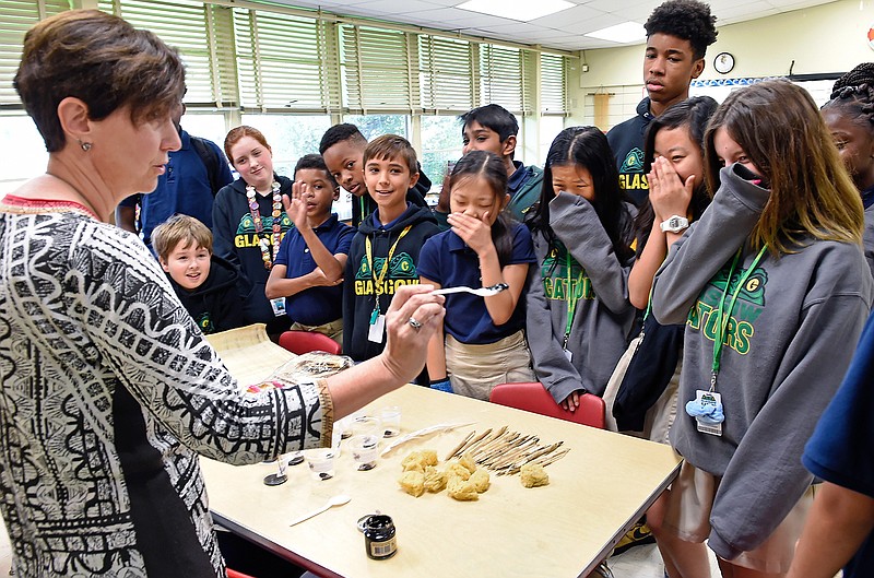 In this Friday, Aug. 23, 2019 photo, Teacher Nathalie Roy, left, talks to her Glasgow Middle School students about using papyrus and learning about writing with smelly squid ink on the papyrus in Baton Rouge, La. This unlikely elective course open to students at Glasgow Middle School in Baton Rouge connects traditional, classical studies with STEM _ short for science, technology, engineering and math. Albeit it is STEM as it existed many centuries ago. (Bill Feig/The Advocate via AP)